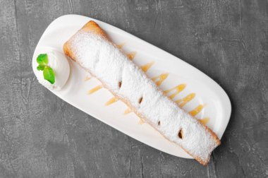 Tarçınlı ve dondurmalı elmalı turta. Nane ve pudra şekeriyle süslenmiş. Beyaz bir tabakta. Yukarıdan bak. Gri beton arkaplan.