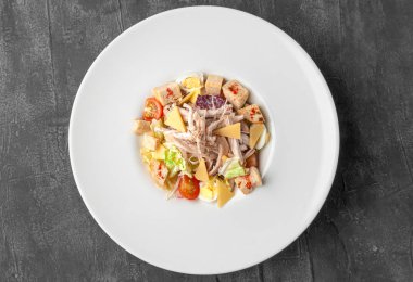 Sezar salatası ve tavuk eti. Büyük beyaz bir tabakta. Yukarıdan bak. Gri beton arkaplan.