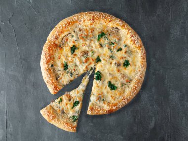 İtalyan pizzası. Tavuk, ıspanak ve mantarla. Kremalı soslu, mozzarella ve sulguni peynirli. Pizzadan bir parça kesilir. Yukarıdan bak. Gri beton arka planda. İzole edilmiş.