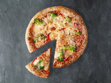 İtalyan pizza vejetaryeni. Brokoli, domates, soğan, domates sosu, mozarella ve sulguni ile. Geniş açılı. Pizzadan bir parça kesilir. Yukarıdan bak. Gri beton arka planda. İzole edilmiş.