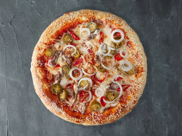 Italian spicy pizza. With chopped beef, onions, hot chili peppers, jalapenos, tomato sauce, cheese. Wide side. View from above. On a gray concrete background. Isolated.