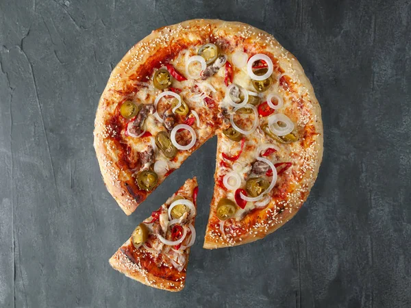 Italian spicy pizza. With chopped beef, onions, hot chili peppers, jalapenos, tomato sauce, cheese. A piece is cut off from pizza. View from above. On a gray concrete background. Isolated. — Stock Photo, Image