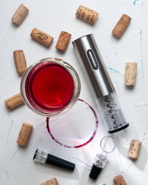 Gri metalden yapılmış elektrikli tirbuşon. Beyaz arka planda. Havalandırıcının yanında ve şarap için vakum mantarının yanında. Bir kadeh şarabın arka planında.