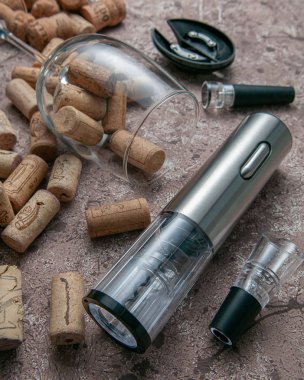 Tirbuşon metalik gri renk. Kahverengi beton arka planda yatıyor. Bardağın, mantarın, havacının yanında şarap için vakum tıpası ve tirbuşon için ayağa kalk..