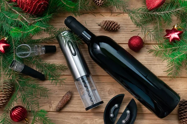 Elektrische kurkentrekker in staal grijs. Aerotar, vacuümkurk en een fles wijn. Op een houten achtergrond. De achtergrond is versierd met kerstspeelgoed en naalden. — Stockfoto