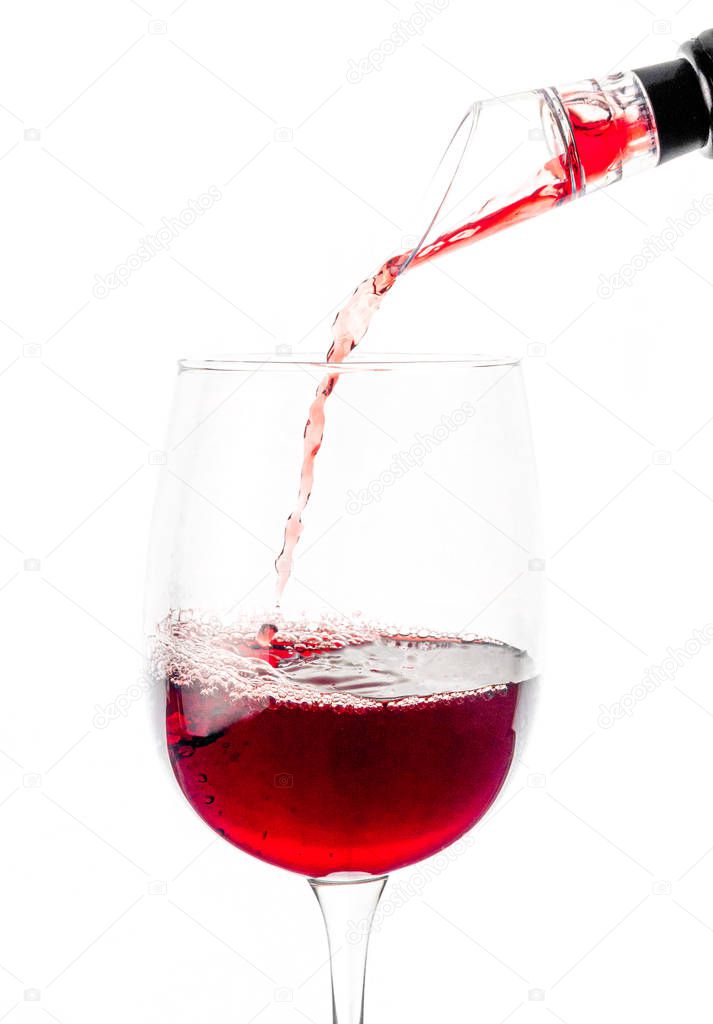 Red wine is poured through aerator into a glass with a thin stream. Isolated. 