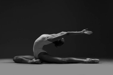 Ballerina posing in pointe shoes and white leotard. Black and white photo