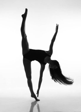 Uzun saçlı esnek bir kız ayakta sicim yapıyor. 