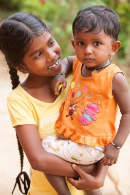 Big sister holds little brother in her arms