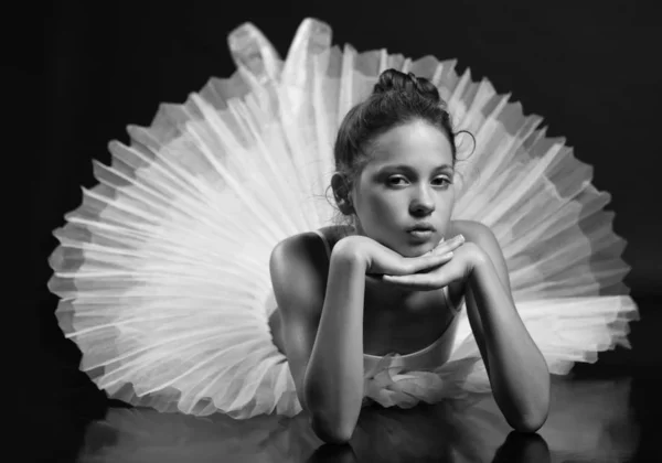 Young girl in ballet tutu posing on the floor
