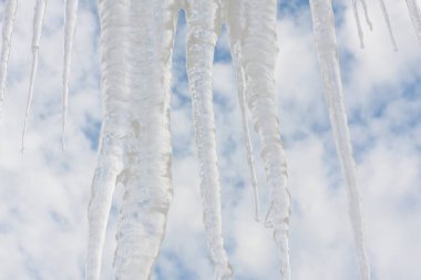 Mavi bulutlu gökyüzü karşı kışın donmuş buz sarkıtları.