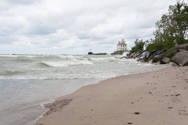 Deniz feneri, akıl hocası burunda Beach State Park Ohio dalgalar çökmesini kıyı ve kara bulutlar yükü ile. 