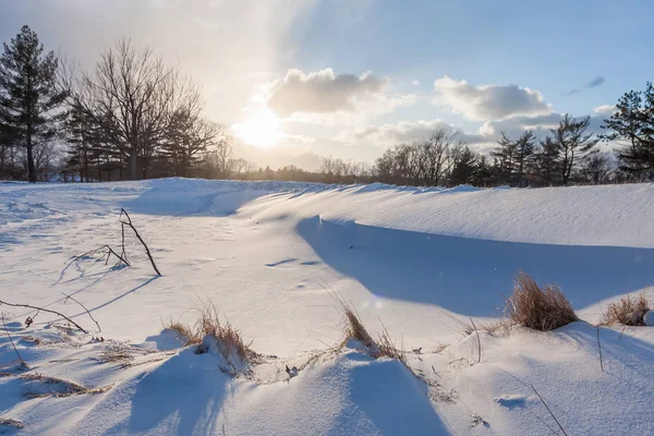 A sandpit at a golf course covered in snow, and the sun setting in the distance. It is now called Acacia metropark.