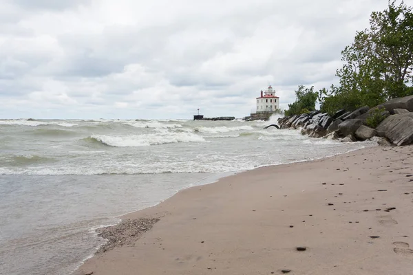 Deniz feneri, akıl hocası burunda Beach State Park Ohio dalgalar çökmesini kıyı ve kara bulutlar yükü ile. 