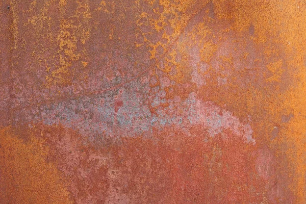 Üzerinde turuncu, kahverengi ve mavimsi desenler olan paslı metalin soyut bir fotoğrafı..