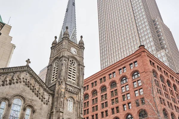 Cleveland Ohio 'daki Eski Taş Kilisesi. Yakındaki binalar ve gökdelenler tarafından cüce gösterilmiş. Anahtar Kule 'nin gölgesinde duruyor. Romen mimarisi yakınlardaki binalara zıt düşüyor.