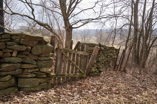 石墙允许通过石墙进入的残破的木制栅栏这堵墙看起来就像从殖民地时期的威廉斯堡乡下的家 — 图库照片