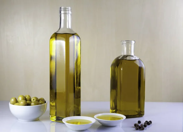 Dos botellas de aceite de oliva con olivo y granos de pimienta — Foto de Stock