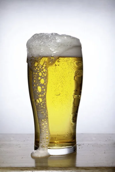 Bicchiere di birra con schiuma su bianco — Foto Stock