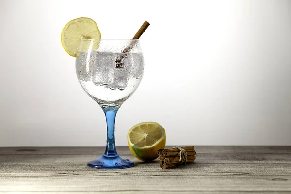 Gin tonic on blue glass with lemon and stick cinnamon — Stock Photo, Image