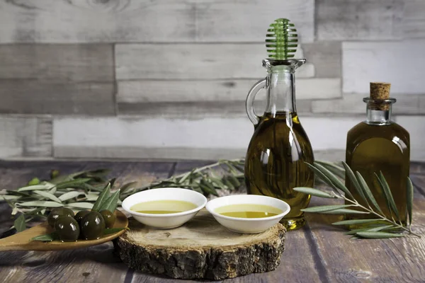 Dos botellas de aceite y un puñado de aceitunas sobre madera — Foto de Stock