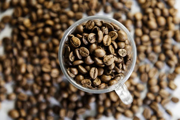 selective focus of coffee beans in a glass cup on unfocused background of coffee beans