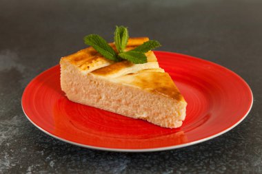 Nane yaprağıyla porsiyon lezzetli cheesecake koyu arkaplan mermerinde kırmızı bir tabakta fotokopi alanı ile