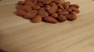 Tahta arka planda dönen bir avuç badem. Boşluğu kopyala 