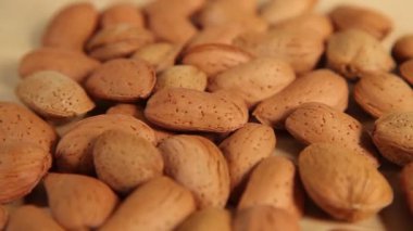Bir avuç badem, ahşap arka planda yakın planda dönüyor. Tam resim 