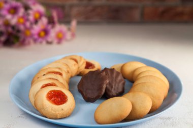 Mavi tabakta çeşitli çaydanlıklar ve beyaz masada çiçekler ve tuğla arka planda