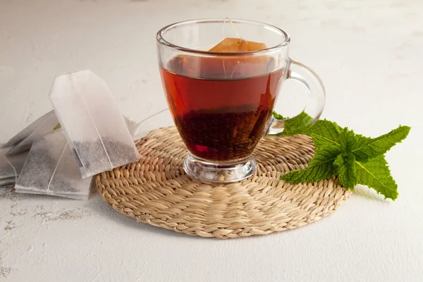 tea cup close-up, tea bags and peppermint leaves  on white table  background