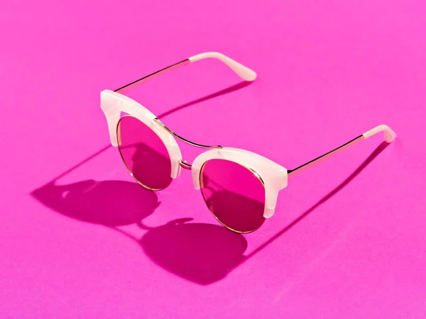 Einzelne Sonnenbrille auf rosa Hintergrund. — Stockfoto