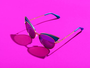 Pembe arka planda tek güneş gözlüğü.