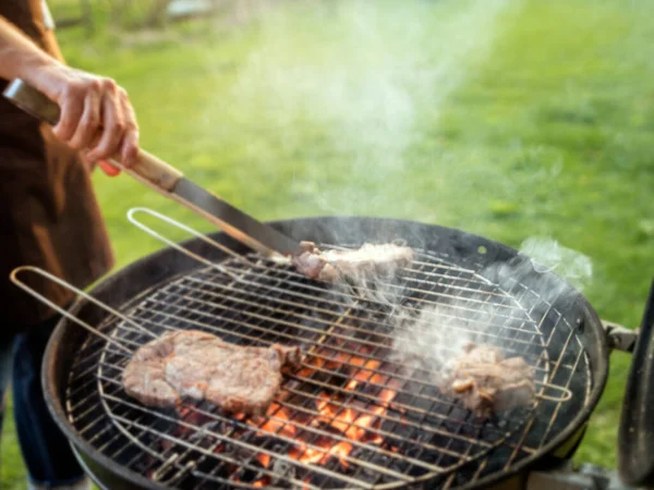 Rozkojarzona scena mężczyzny grillującego mięso na świeżym powietrzu. — Zdjęcie stockowe