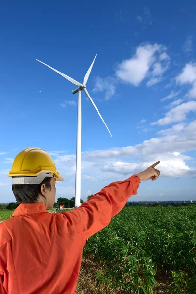 A workwer in safety suit and yellow helmet with Wind turbines ge