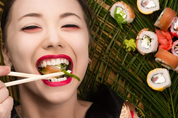 Piękny uśmiechający się młody Koreański dziewczyna jedzenia sushi rolls — Zdjęcie stockowe