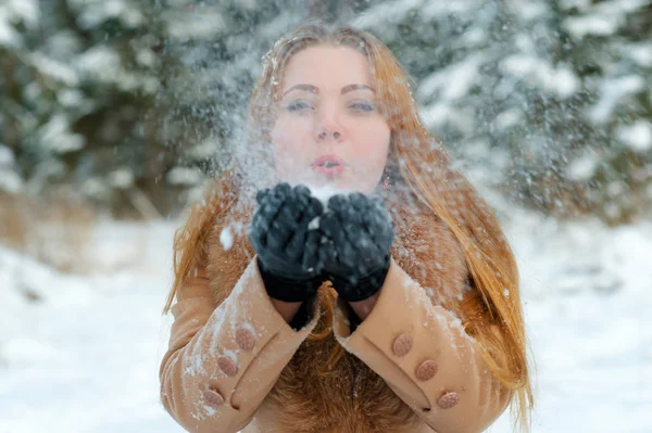 Ελκυστική γυναίκα που φυσάει χιόνι στα χέρια — Φωτογραφία Αρχείου