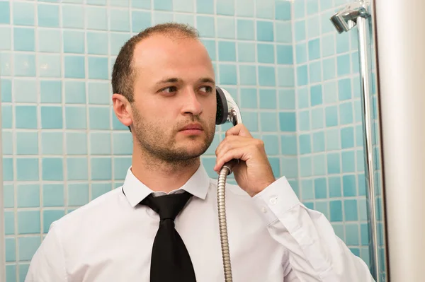 Серьезный красивый бизнесмен, стоящий в ванной комнате с душем в руке — стоковое фото