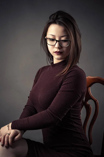 Портрет задумчивой молодой девушки, сидящей на стуле — стоковое фото