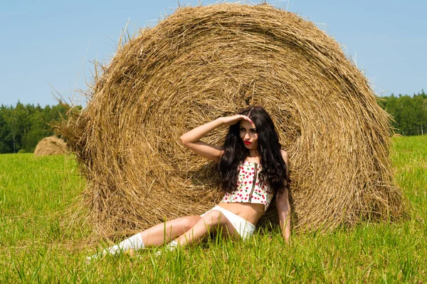 Молодая модная женщина лежит на траве на стоге сена — стоковое фото