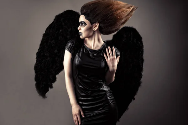 Mulher luxuosa com cabelo exuberante e maquiagem escura com asas pretas — Fotografia de Stock