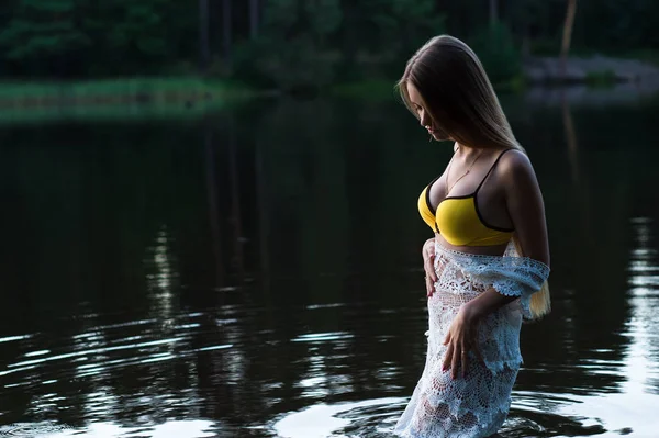 Joven adolescente chica en vestido blanco y traje de baño amarillo de pie en el agua —  Fotos de Stock