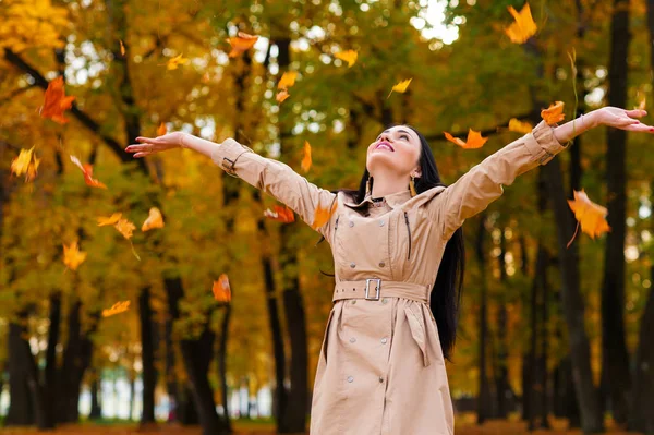 Счастливая женщина бросает осенние листья вверх — стоковое фото