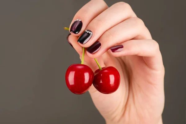 Beautiful juicy cherry in female hand with luxurious manicure — Stock Photo, Image
