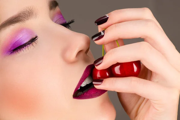 Beautiful girl with bright makeup eating cherry — Stock Photo, Image