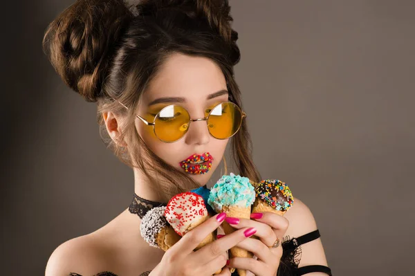 Αισθησιακή γυναίκα με κίτρινα γυαλιά και πολύχρωμο μακιγιάζ στα χείλη με το παγωτό στα χέρια — Φωτογραφία Αρχείου