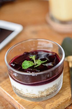 Blueberry Cheese Cake ahşap plaka üzerinde cam kapta.