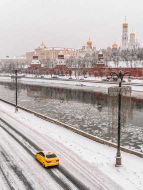 Sarı taksi araba kışın Moskova Kremlin önünde. Kış görünümü Moskova Kremlin ve Moskova Nehri sarı Taksi arabası ön planda olan yoğun kar yağışı sonra.