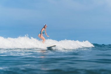 woman in swimming suit surfing in ocean clipart