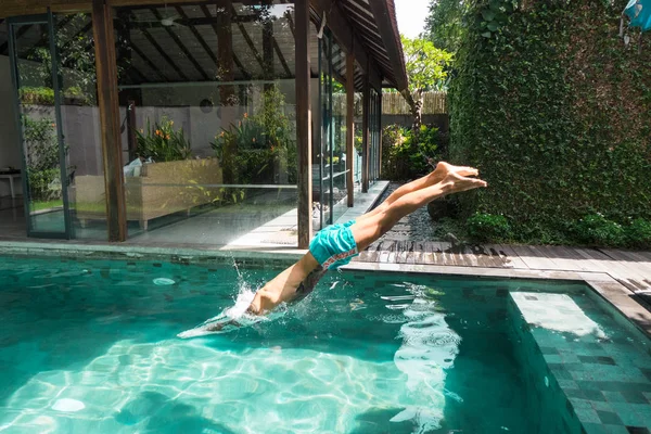 Vista lateral del hombre tatuado buceando en la piscina durante las vacaciones en bali, indonesia — Stock Photo